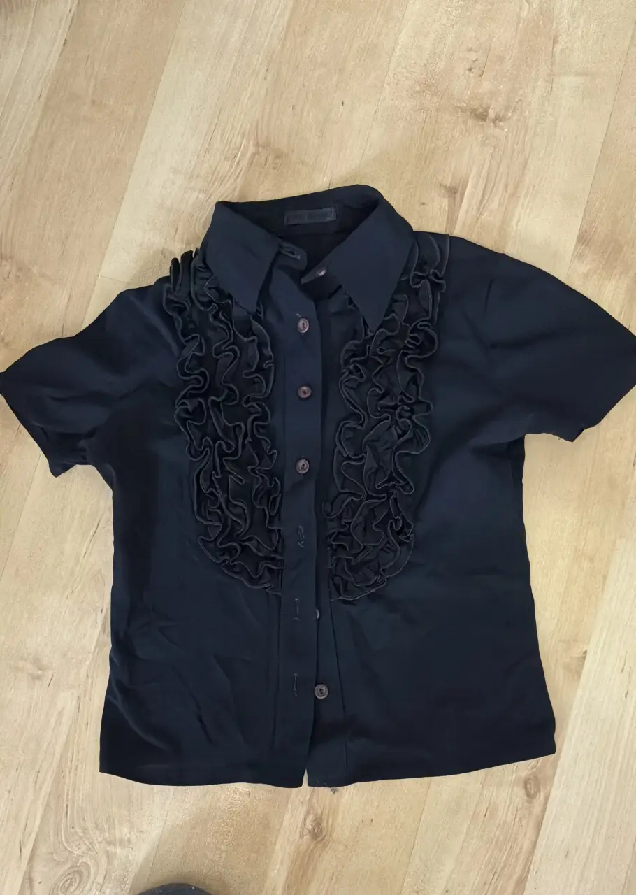 Blusa negra con detalle de volados en el frente. Ideal para un look elegante y sofisticado.