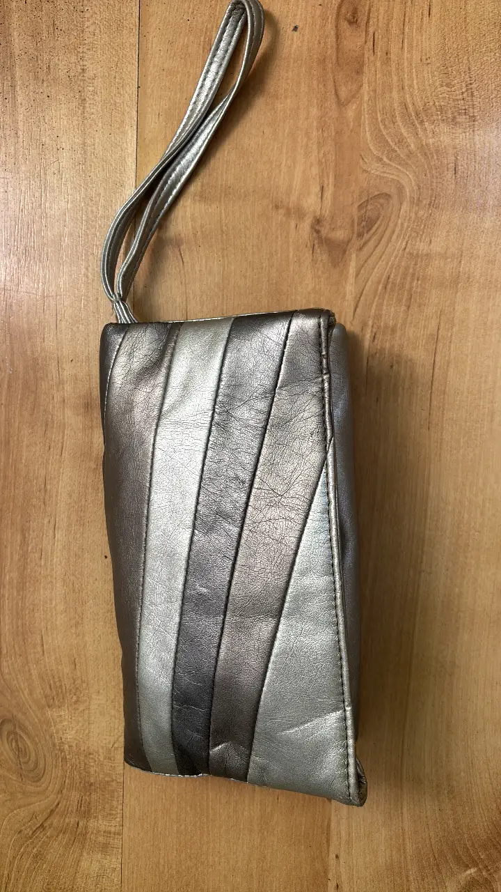 Cartera plateada Sybilla, con cierre y manija para llevar en la mano. Ideal para eventos.
