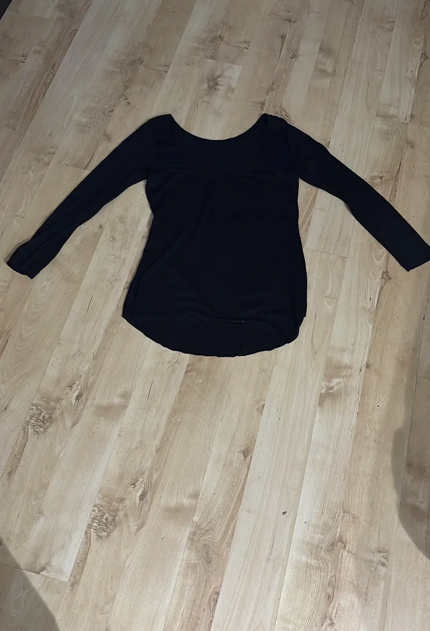 Remera manga larga negra, elegante con escote en la espalda. Ideal para un look casual y cómodo.