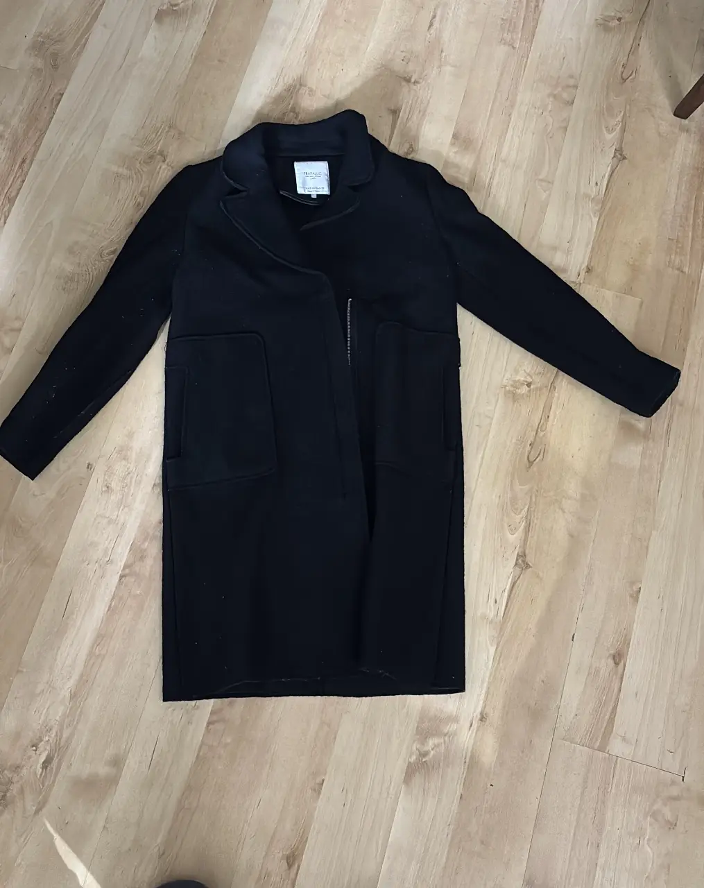 Tapado con cierre look muy casual/ largo negro modelo Trafaluc, ideal para el invierno. Posee dos bolsillos delanteros y un corte clásico.