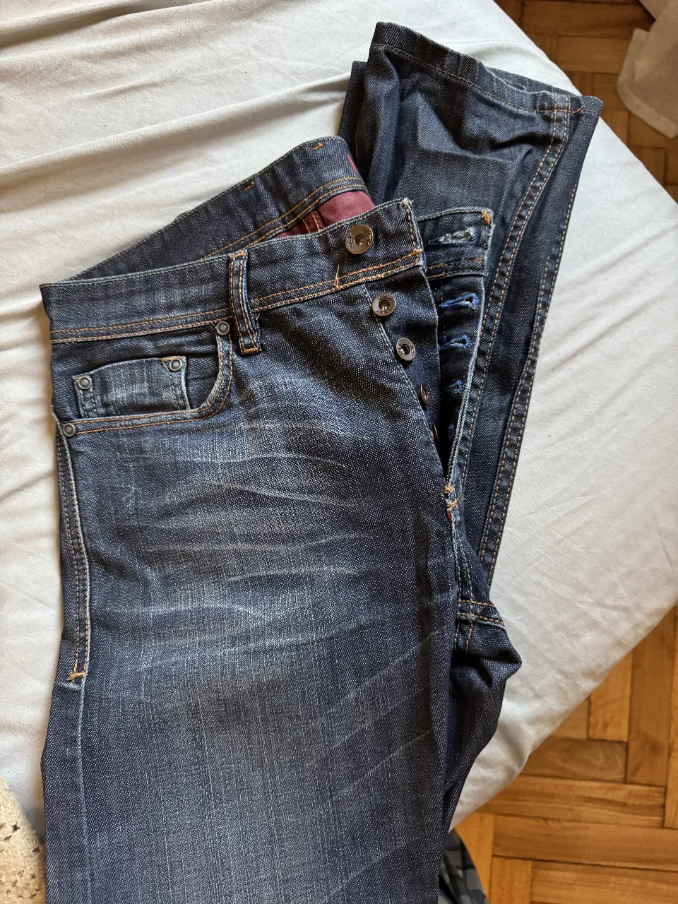 Jeans rectos de hombre, azul oscuro, con detalles de desgaste y botones. Talle 28.