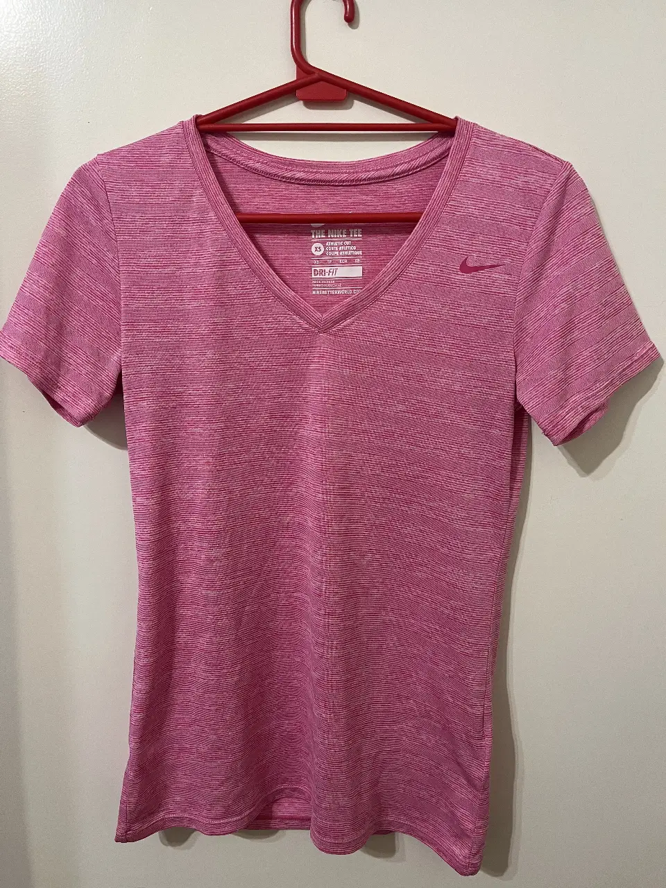 Remera deportiva Nike Dri-Fit para mujer, color rosa con finas líneas blancas. Talle XS. Ideal para entrenamientos.