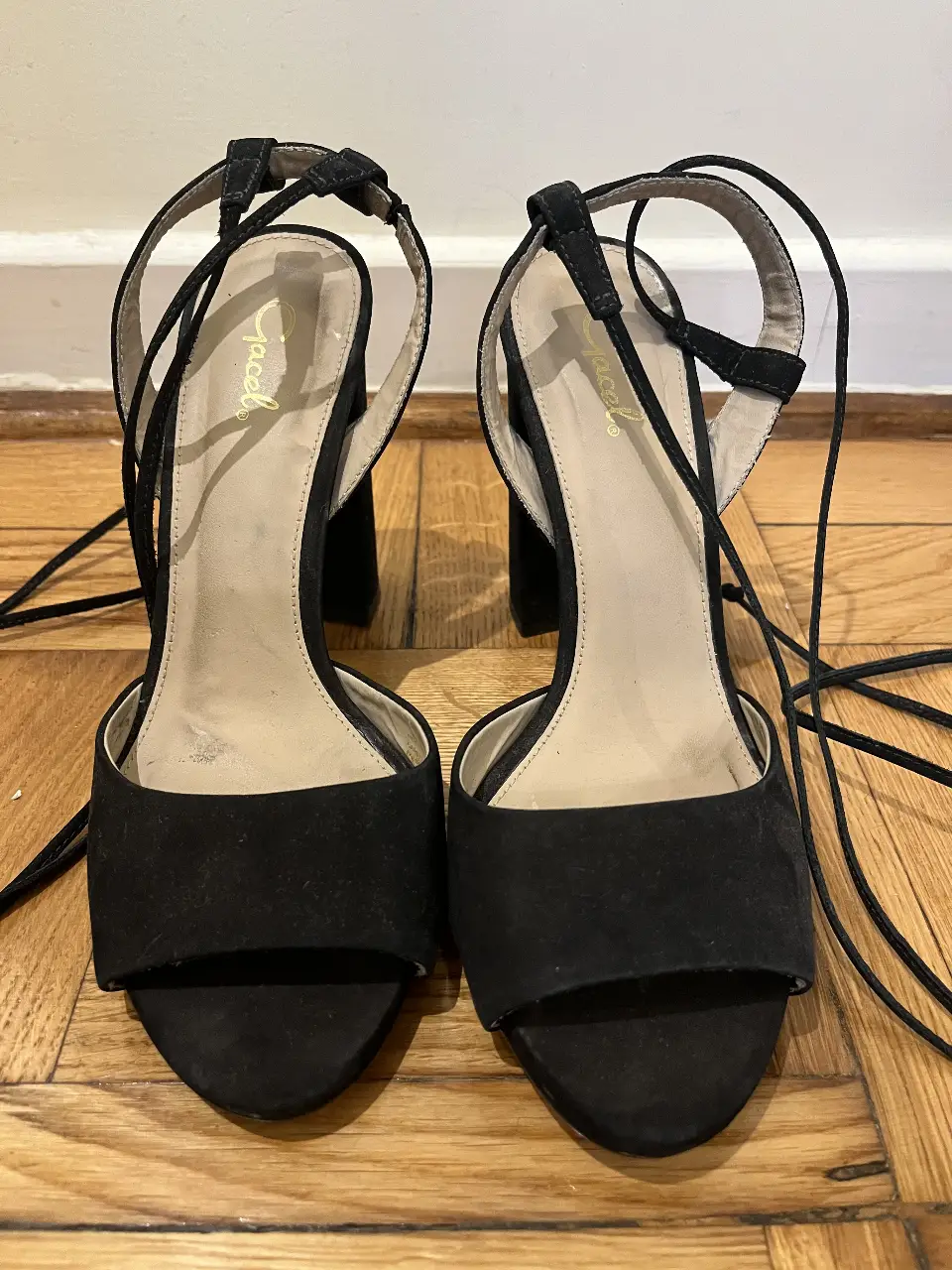 Sandalias de taco alto negras con tiras para atar al tobillo. Ideales para fiestas y eventos.