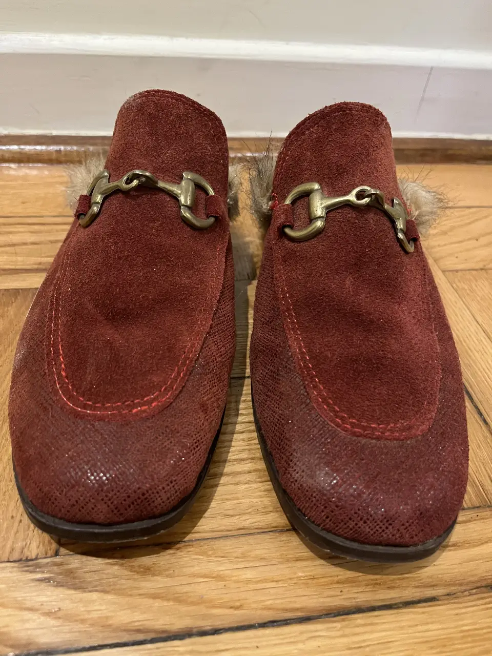 Mocasines  de  color rojo con detalle de hebilla dorada y pelaje en el borde. Ideales para un look elegante y cómodo.