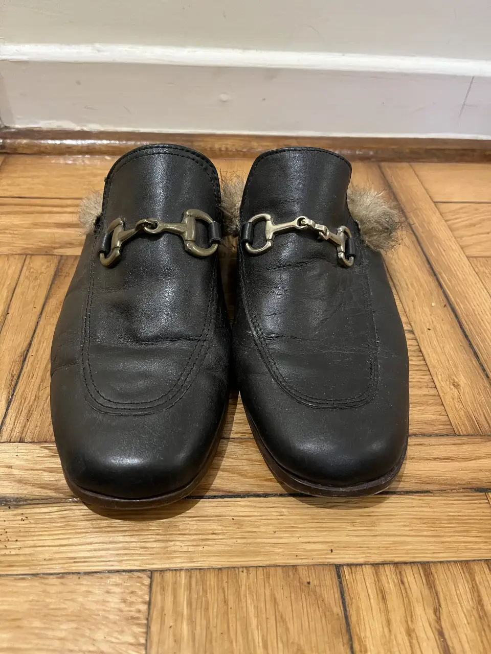 Mocasines  de cuero negro con detalle de hebilla dorada y pelaje en el interior. Un calzado elegante y cómodo para cualquier ocasión.