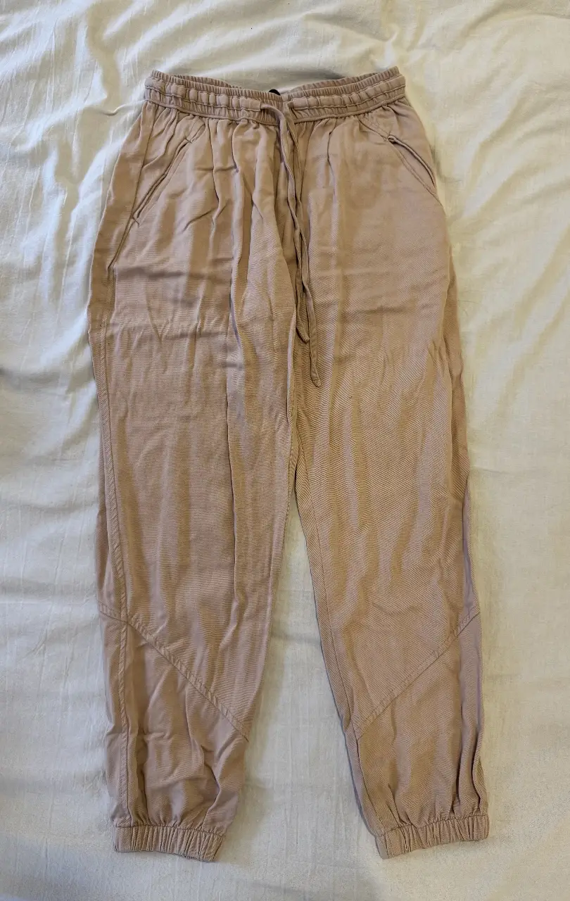 Pantalón suelto de mujer, color crudo. Con cintura elastizada y cordón para ajustar. Ajustado en los tobillos. Bolsillos laterales y detalles de costura en las rodillas. Talle S. Ideal para un look casual y MUY cómodo.