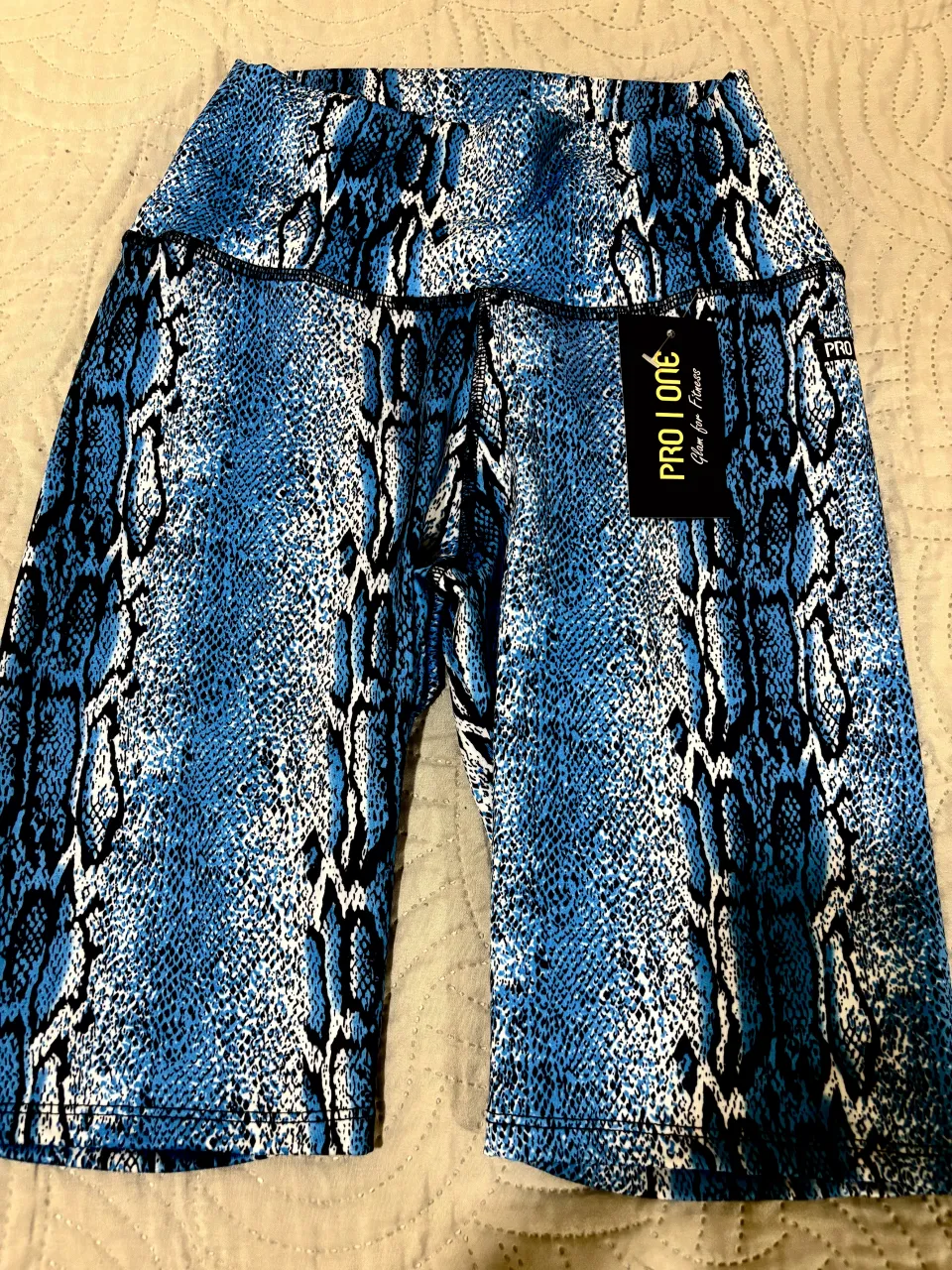 Shorts deportivos con estampado de escamas de serpiente en tonos azules y blancos. El segundo par de shorts tiene un estampado galáctico en tonos púrpuras y azules.