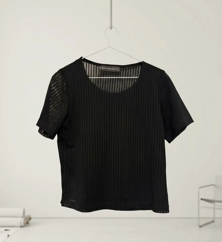 Remera negra de manga corta con un diseño de rayas verticales finas y sutiles. La tela es ligera y con transparencia, ideal para un look moderno y sofisticado. Perfecta para combinar con otras prendas y crear outfits únicos. Poco uso.