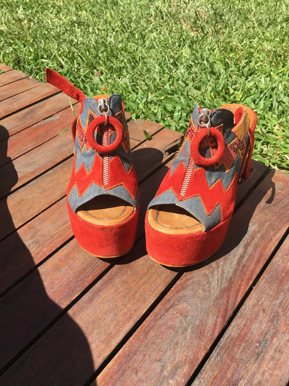 Sandalias de plataforma rojas con detalles en azul y naranja. Diseño con cierre y plataforma alta, ideales para un look audaz y moderno.