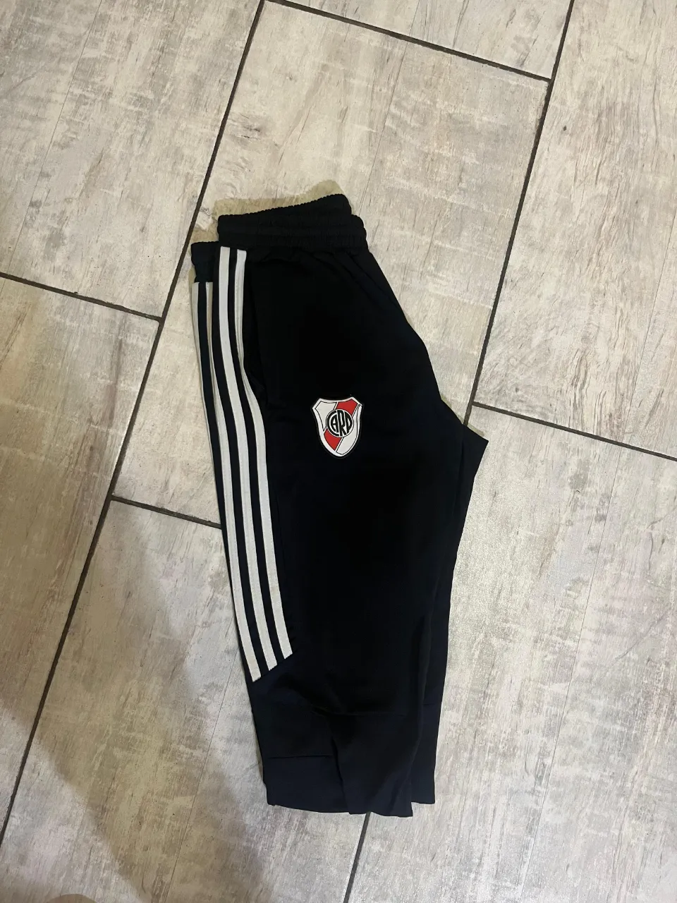 Pantalon deportivo negro con detalles de Adidas y escudo de River Plate. Ideal para los fanáticos del fútbol y para entrenar.