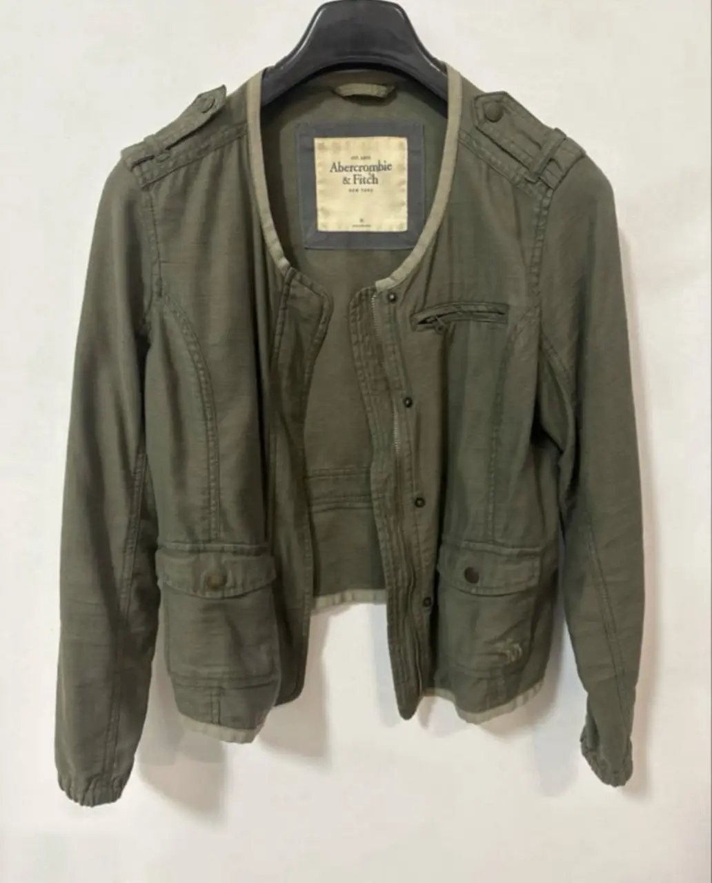 Campera Abercrombie & Fitch verde militar, estilo bomber, con bolsillos y detalles de diseño. Ideal para un look casual y canchero.