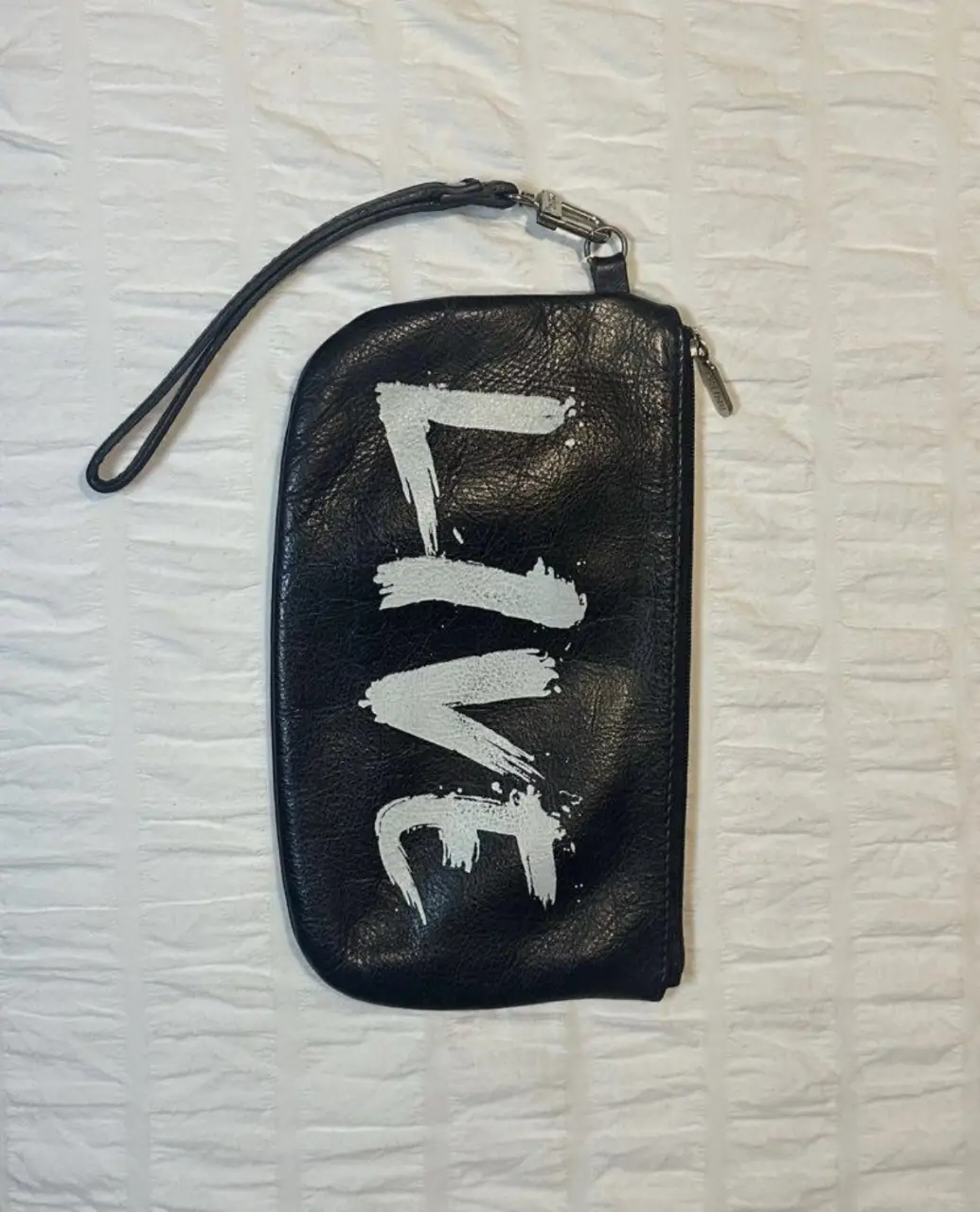 Cartera de mano negra con la palabra "LIVE" en blanco. Ideal para llevar lo esencial con estilo.