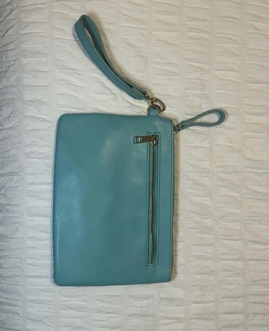 Cartera de mano celeste, ideal para llevar lo esencial con estilo. Cuenta con un cierre lateral y una manija para mayor comodidad. Perfecta para complementar cualquier look.