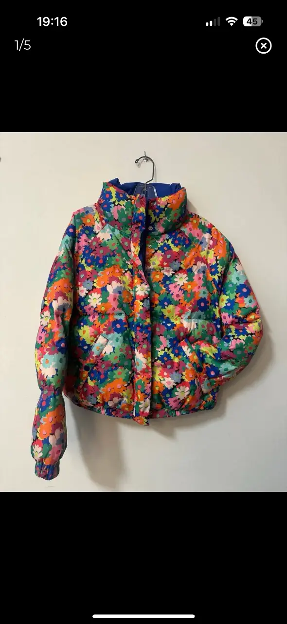 Campera puffer con estampado floral vibrante. Diseño acolchado, cuello alto y cierre con botones y cremallera. Ideal para un look moderno y abrigado.