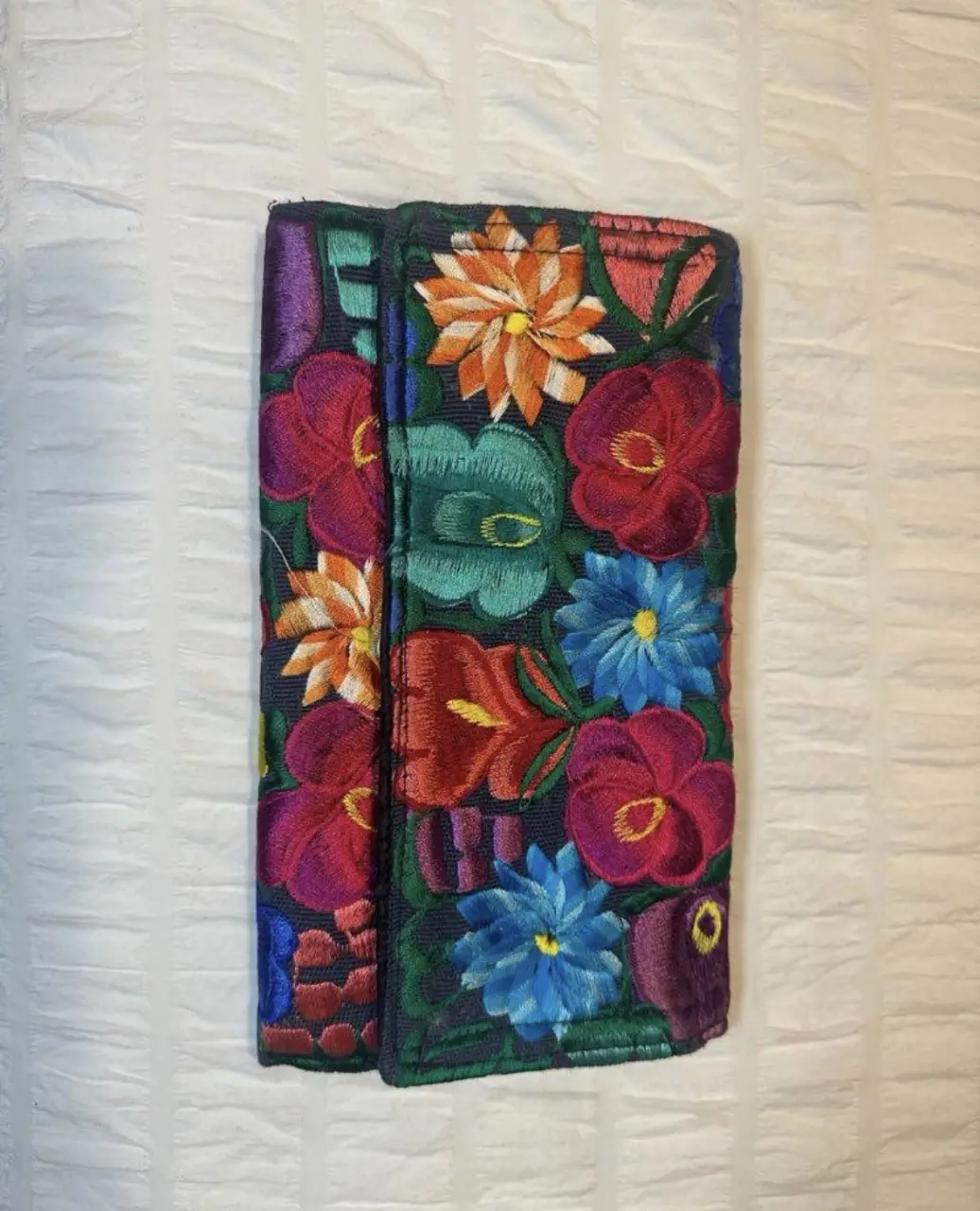 Clutch artesanal bordada con flores, ideal para guardar tus pertenencias con estilo y un toque de color. 