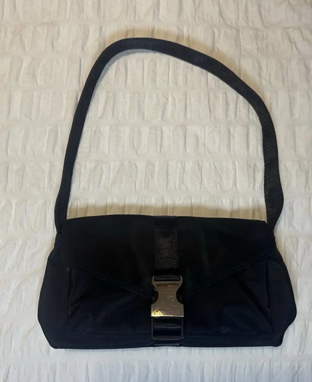 Cartera negra, con cierre de hebilla metálica. Ideal para llevar lo esencial con estilo y practicidad. Perfecta para un look casual o para complementar un outfit más arreglado.