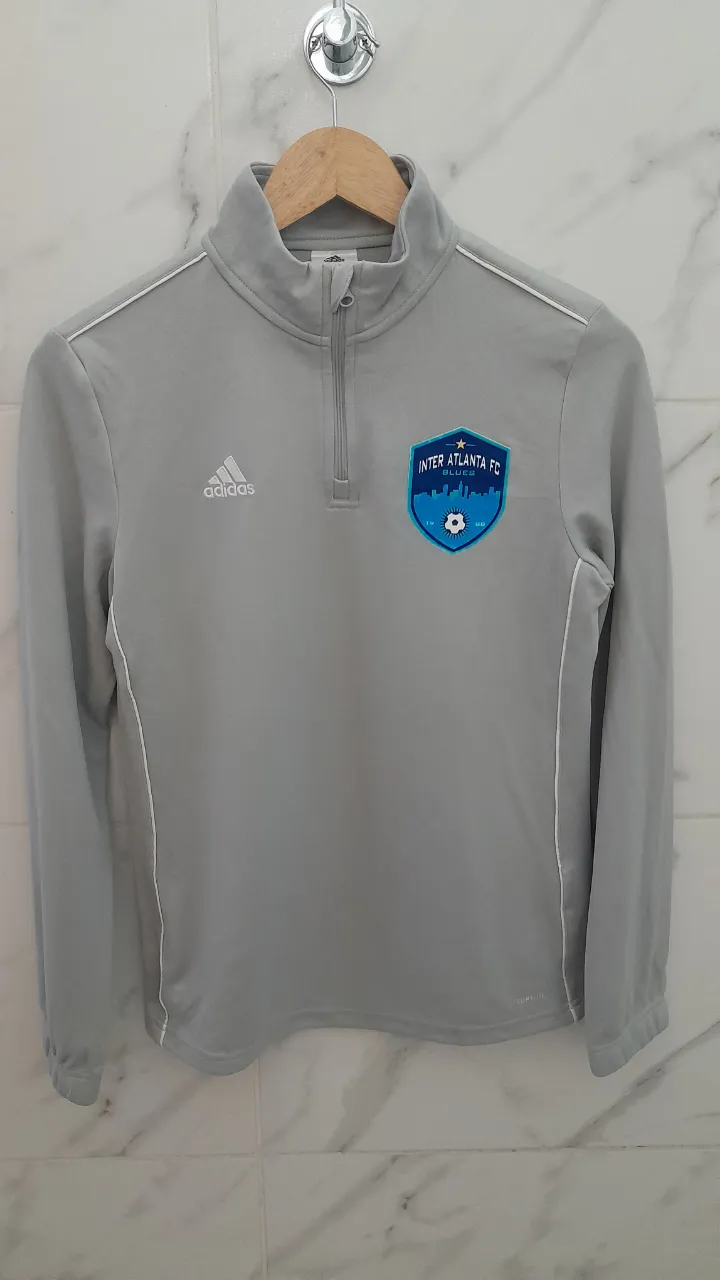 Buzo deportiva gris de manga larga con cierre en el cuello y logo de Inter Atlanta FC en el pecho. Marca Adidas.