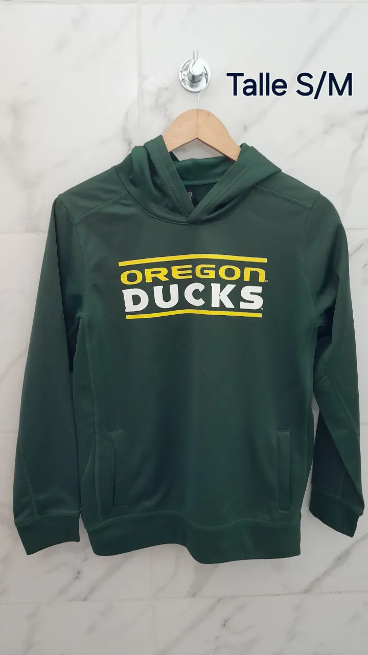 Buzo con capucha de color verde oscuro. Estampa frontal con el texto "OREGON DUCKS" en amarillo y blanco. Posee bolsillos tipo canguro.