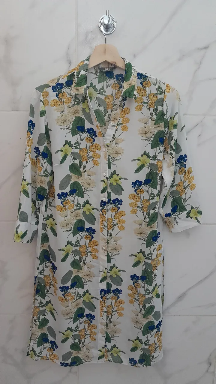 Camisa estampada con flores en tonos blanco, amarillo, azul y verde. Manga 3/4, cuello camisero y botones al frente. Ideal para un look casual y fresco.