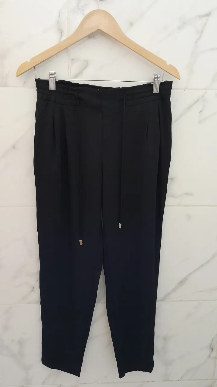 Pantalón negro de vestir con cordón ajustable en la cintura y bolsillos laterales.