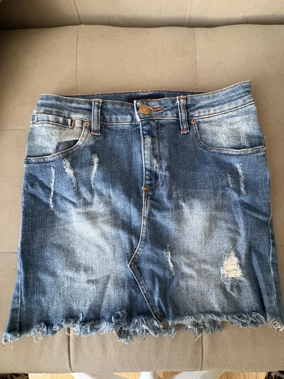 Min de jean Tucci azul con detalles rotos y flecos en el borde inferior. Talle S, ideal para un look casual y moderno.
