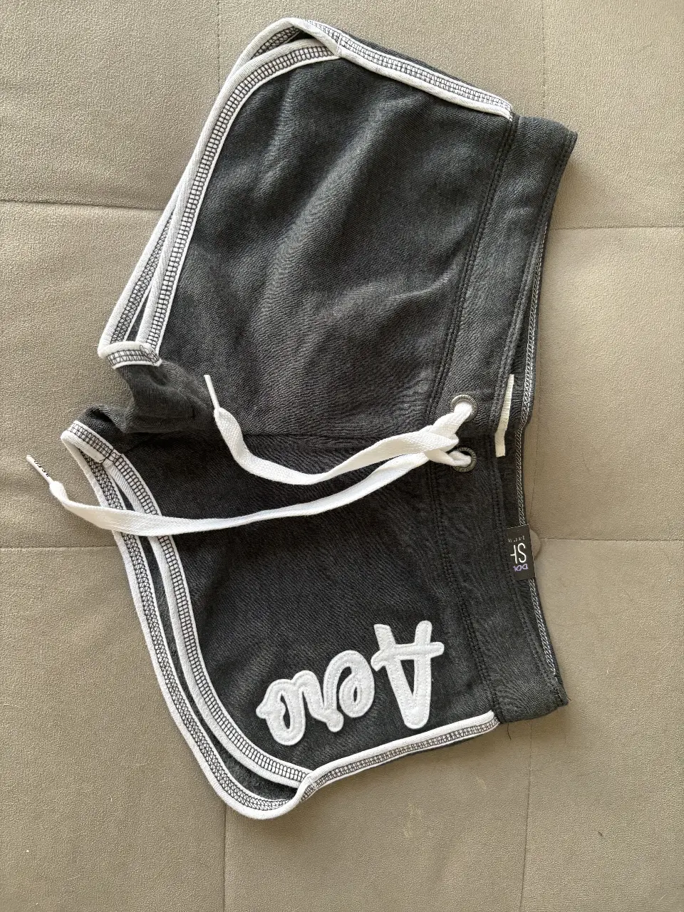 Short Aeropostale deportivo de mujer, color gris oscuro con detalles en blanco. logo "Aero" bordado. Ideal para actividades físicas o uso casual.