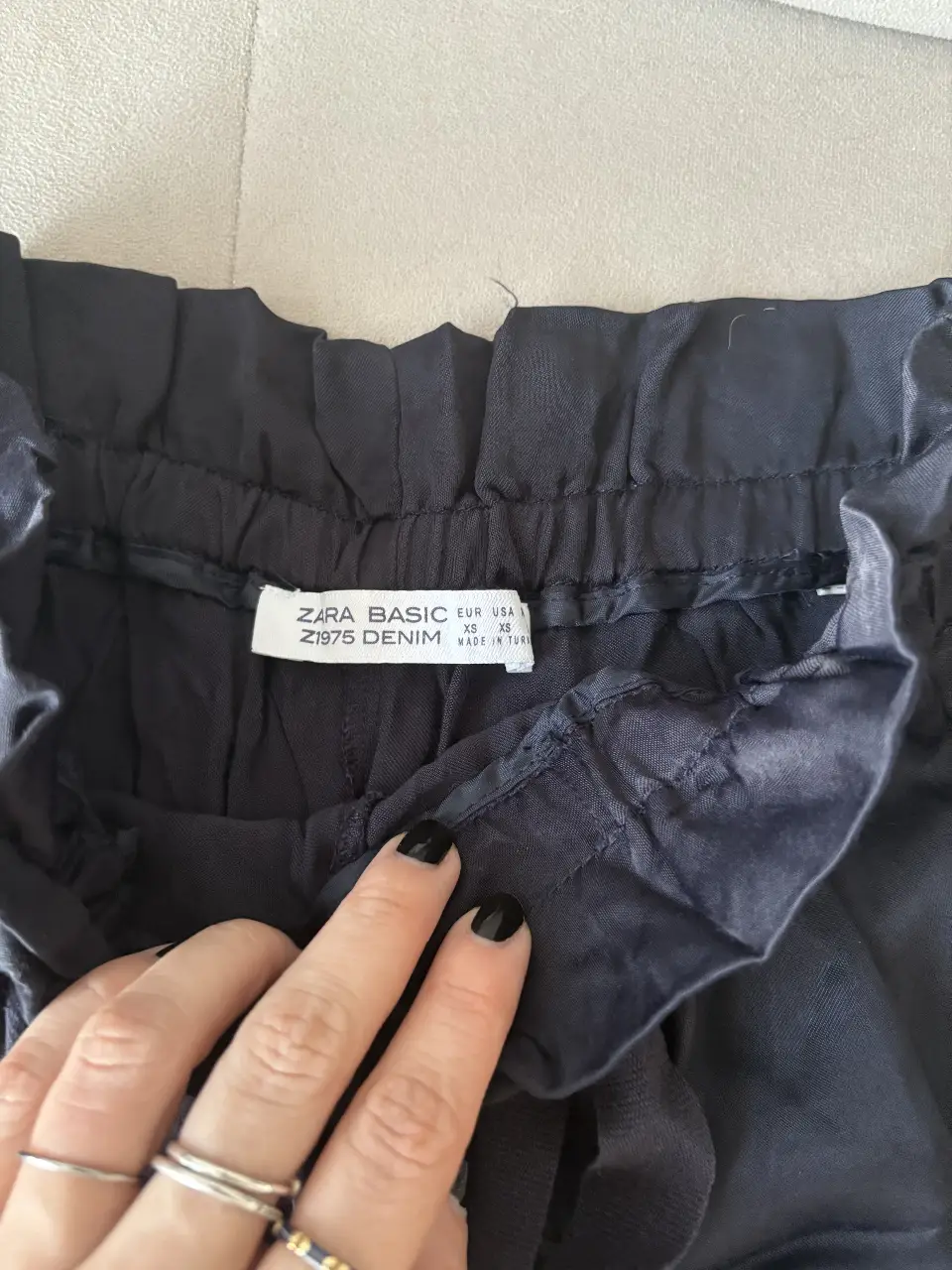 Short negro de tela con detalles en rojo y plateado en los laterales. Tiro alto, con cintura elastizada y lazo para ajustar. Ideal para un look casual y cómodo.