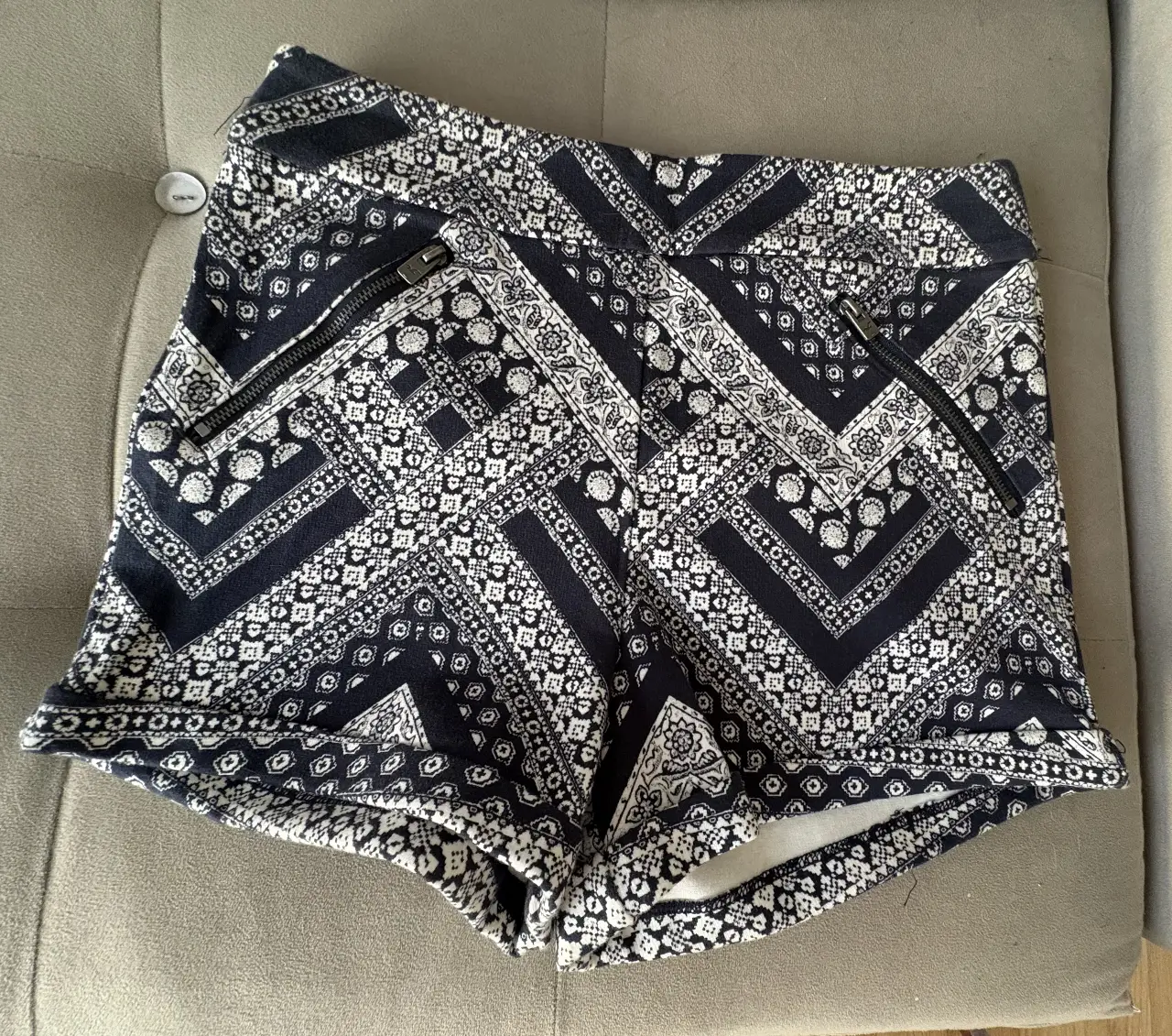 Shorts de mujer Hollister con estampado geométrico en blanco y negro. Tiro alto, con bolsillos con cierre y dobladillo en la basta. Ideal para un look casual y moderno.