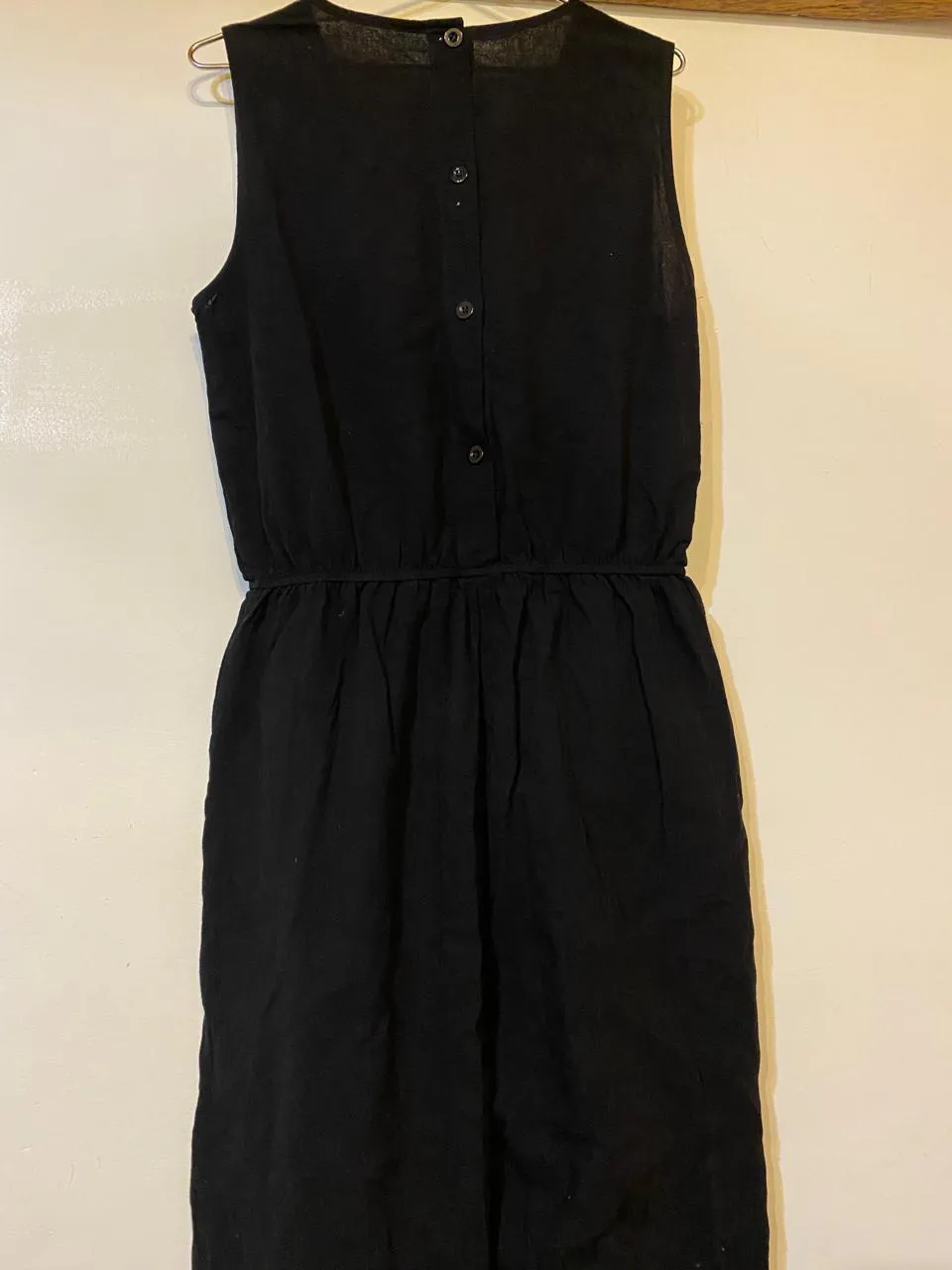 Vestido negro sin mangas con botones en la espalda y cintura elastizada.