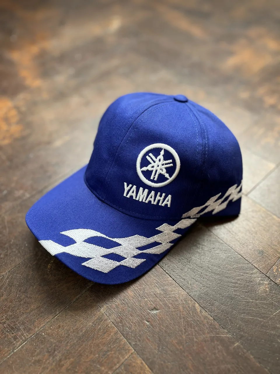 Gorra azul de Yamaha con logo bordado y detalles de diseño en blanco. 