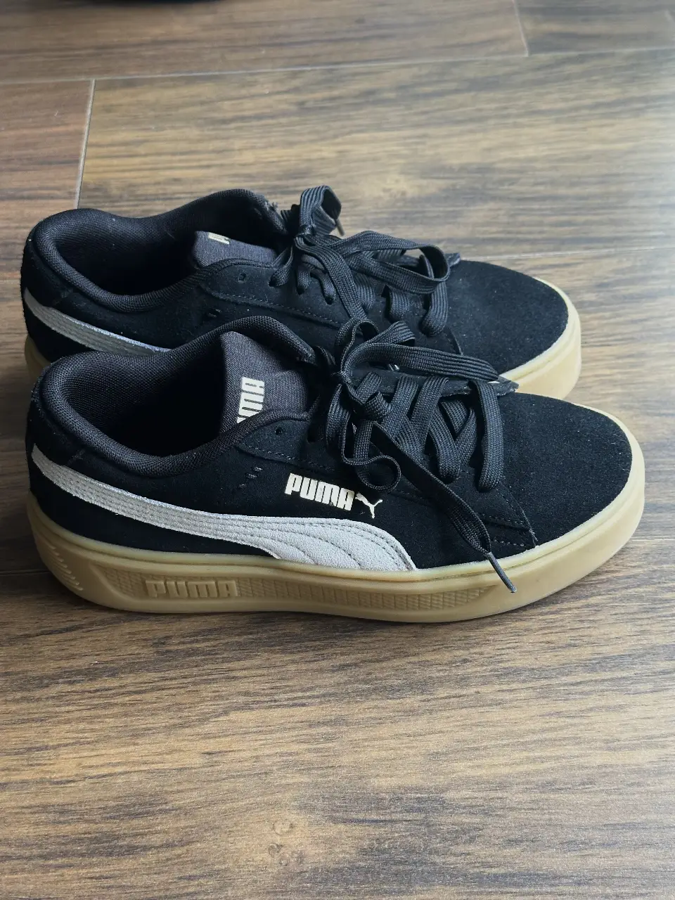 Zapatillas Puma negras con detalles en blanco y suela color crema. Ideales para un look casual y cómodo.