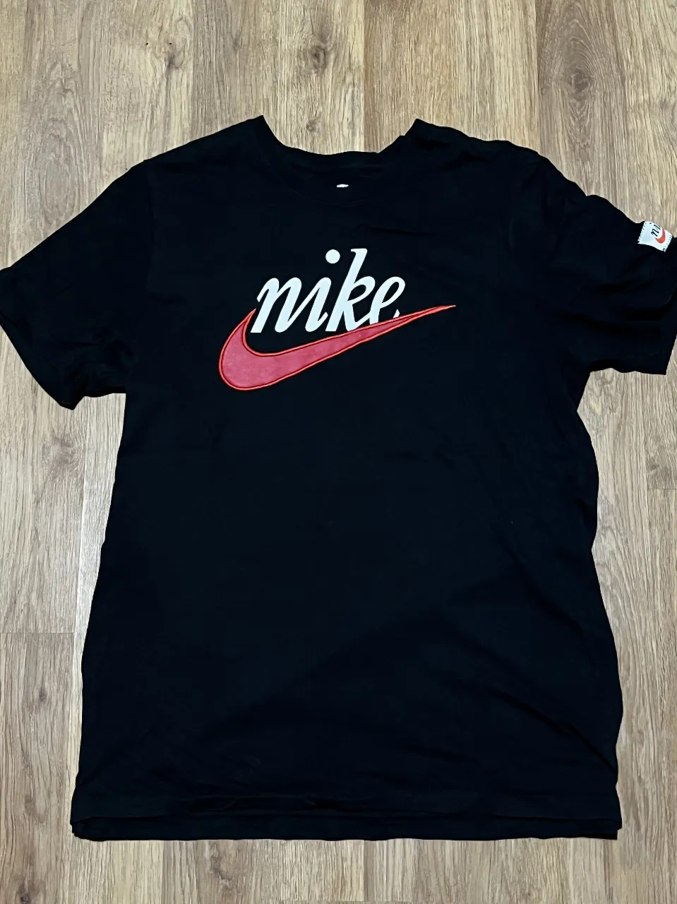 Remera negra de algodón con el icónico logo de Nike en rojo y blanco. Un clásico para el día a día.