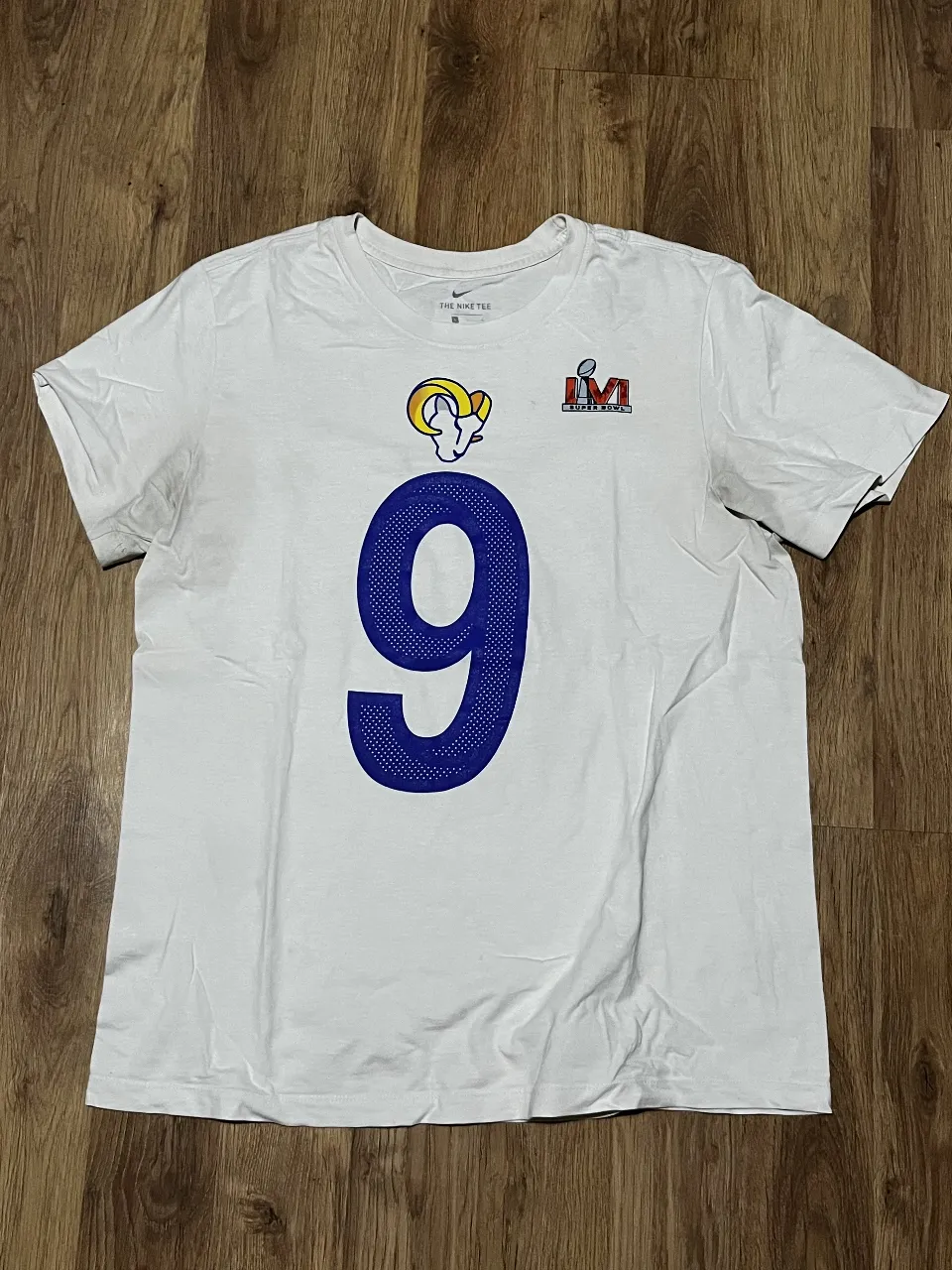 Remera blanca de algodón con estampa del equipo de fútbol americano Rams. En el frente, el número 9 en azul y el logo del equipo. En la espalda, el nombre STAFFORD y el número 9 en azul. Ideal para fanáticos del deporte.
