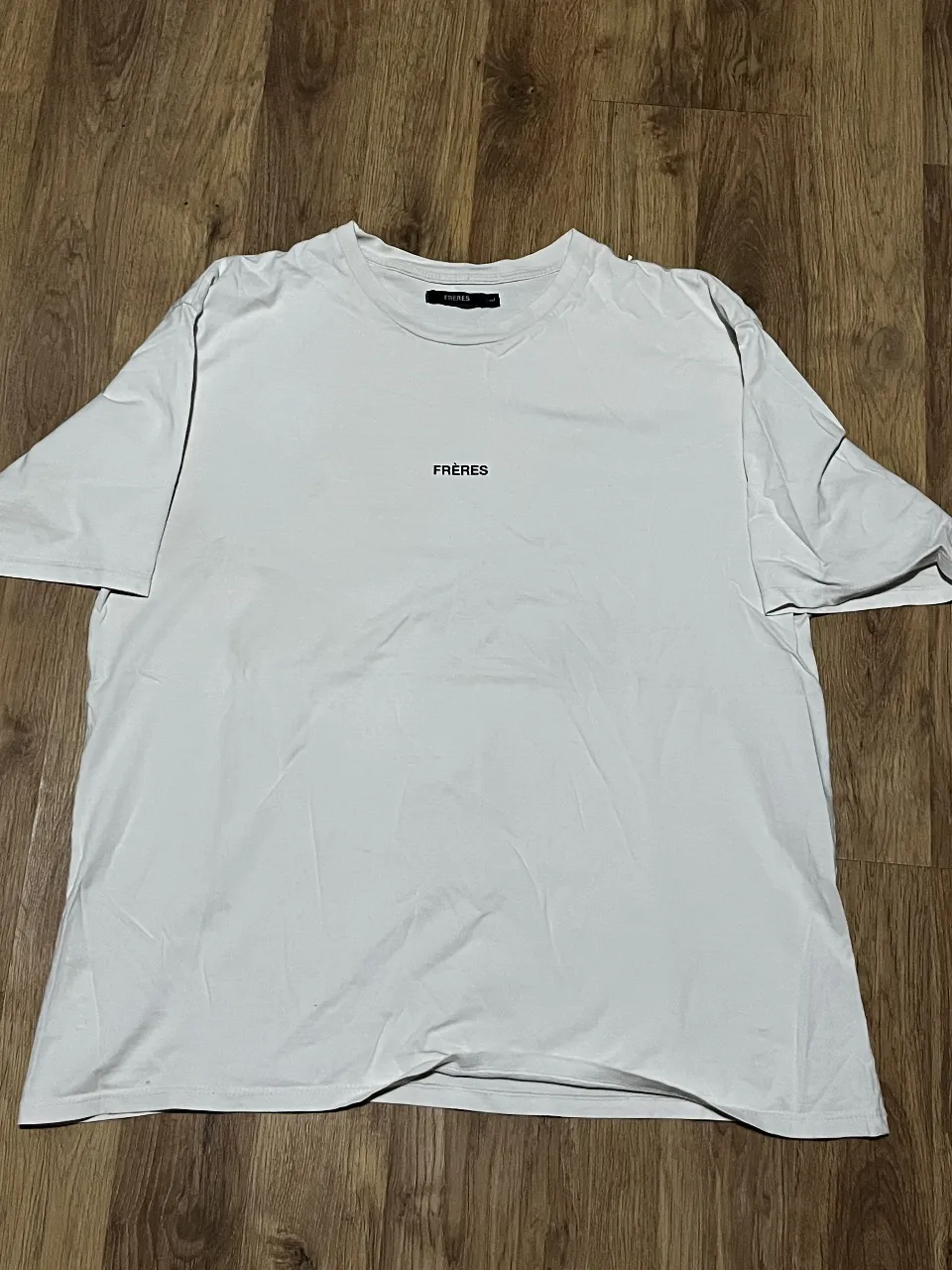 Remera blanca de manga corta con estampa minimalista de la marca FRERES. Diseño moderno y versátil, ideal para cualquier ocasión.