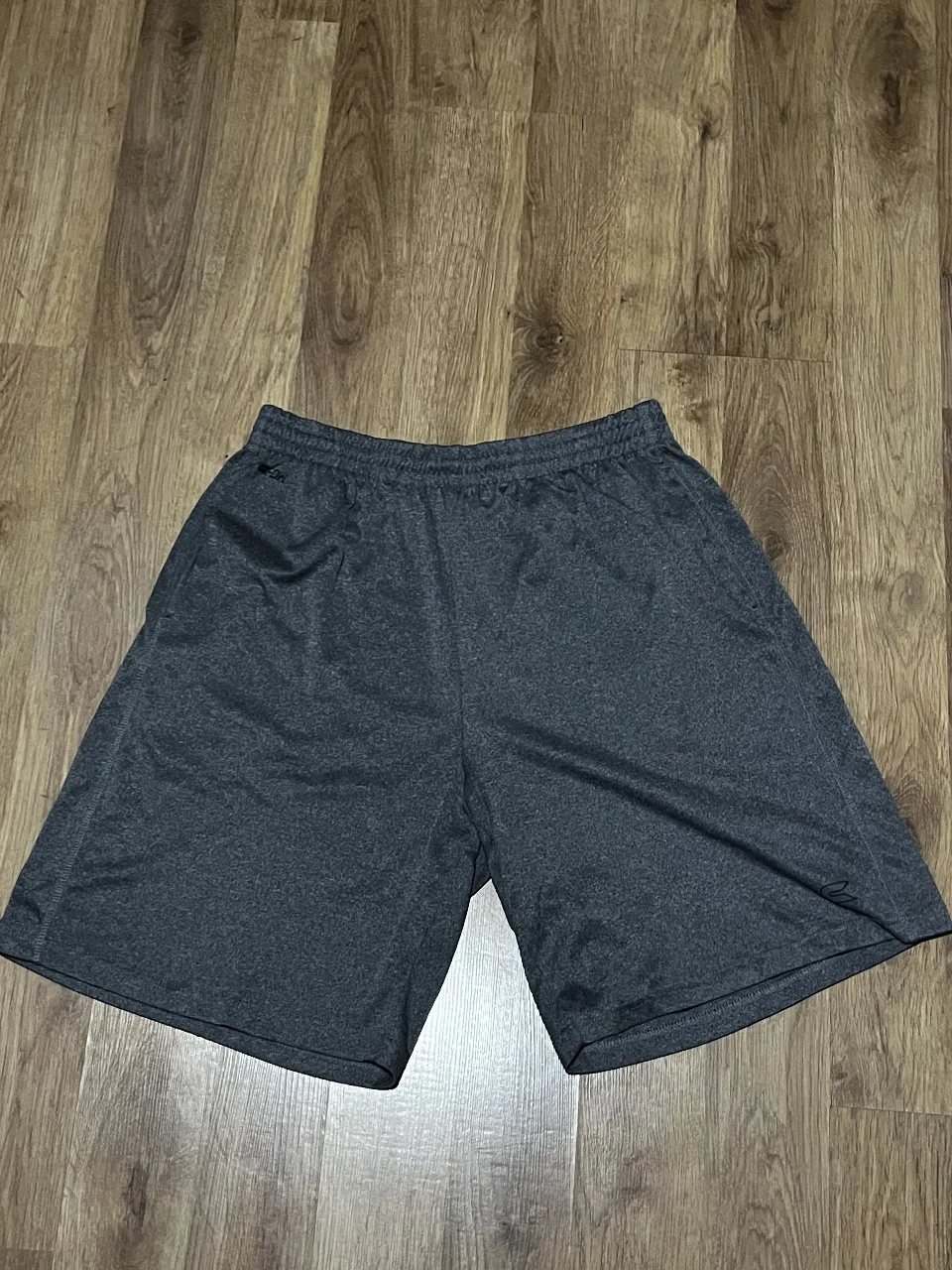 Shorts deportivos grises, ideales para entrenar o para estar cómodo en casa. Tienen cintura elastizada y bolsillos laterales.