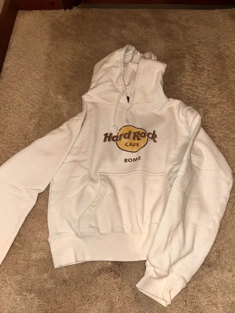 Buzo canguro blanco de algodón con capucha y bolsillo frontal. Estampado "Hard Rock Cafe Rome" en el frente. Ideal para un look casual y urbano.