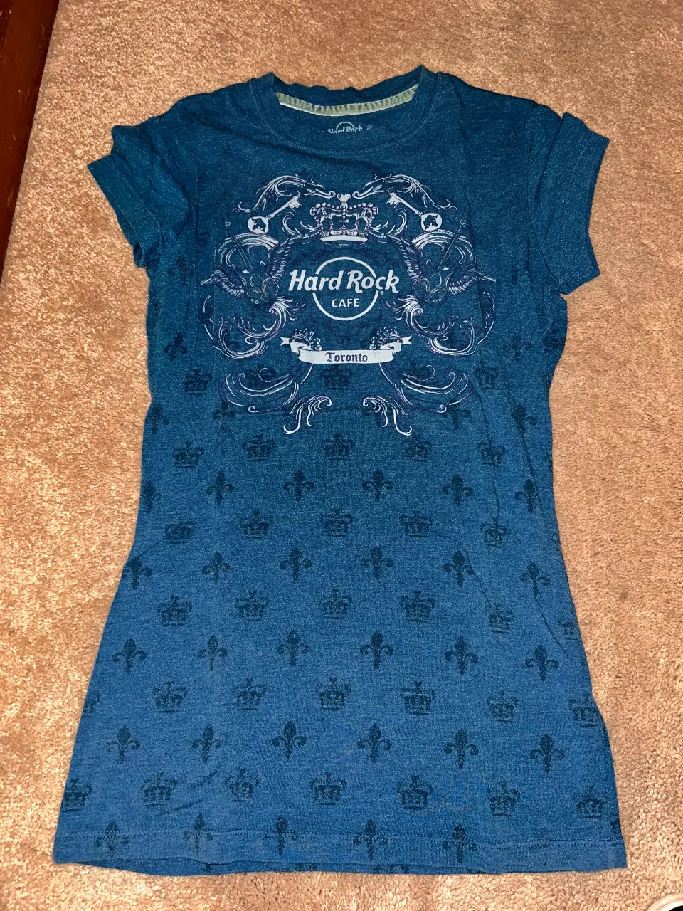 Remera de mujer Hard Rock Cafe Toronto, de manga corta, con estampado frontal y trasero de coronas y el logo de la marca. Ideal para un look casual y urbano.