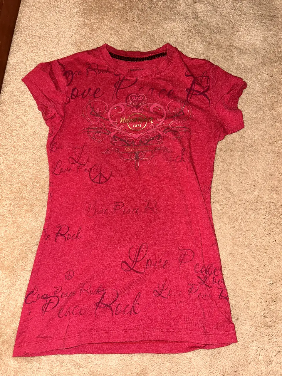 Remera fucsia de Hard Rock Cafe Boston, con estampado de "Love Peace Rock" y el logo de la marca. Ideal para un look casual y con onda.