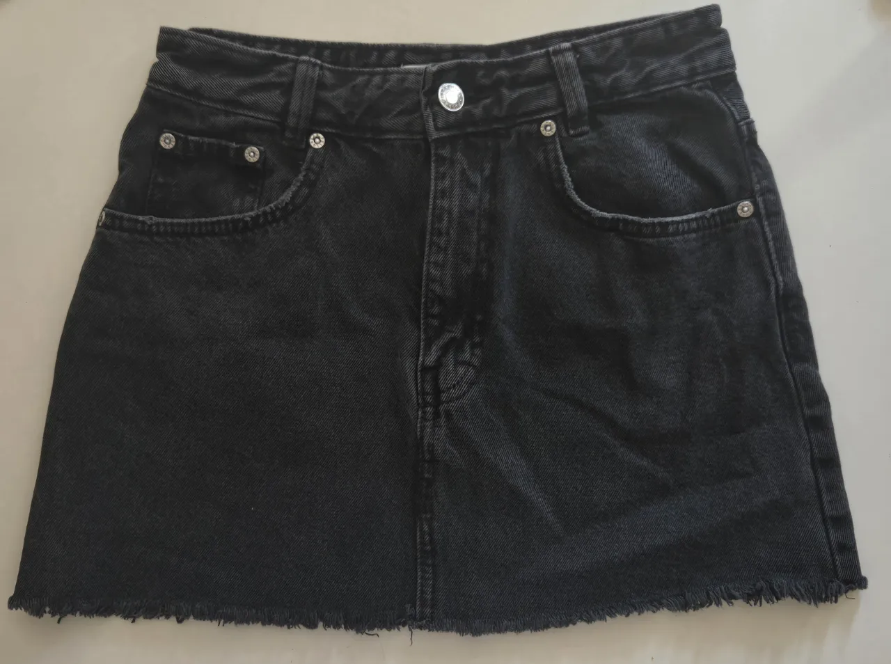 pollera de jean negra con flecos en el ruedo. tiene bolsillos delanteros y traseros.