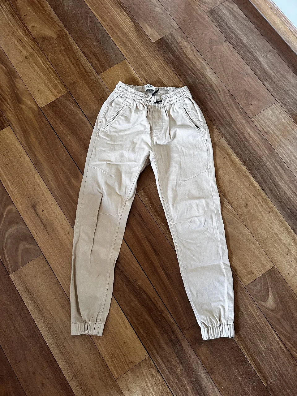 Pantalón chino de hombre color crudo, con cintura elastizada y puños en los tobillos. Talle 28, ideal para un look casual y cómodo.