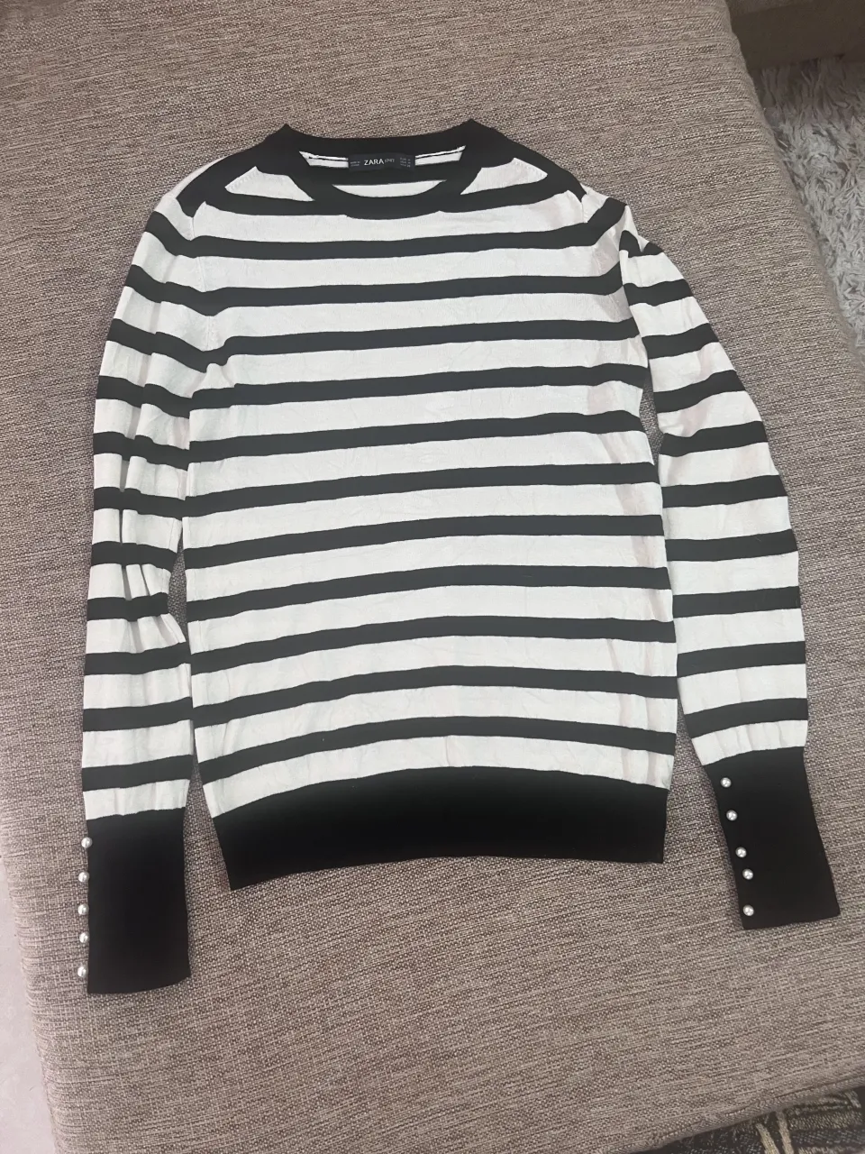 Sweater de mangas largas a rayas blancas y negras. Puños anchos negros con botones nacarados.