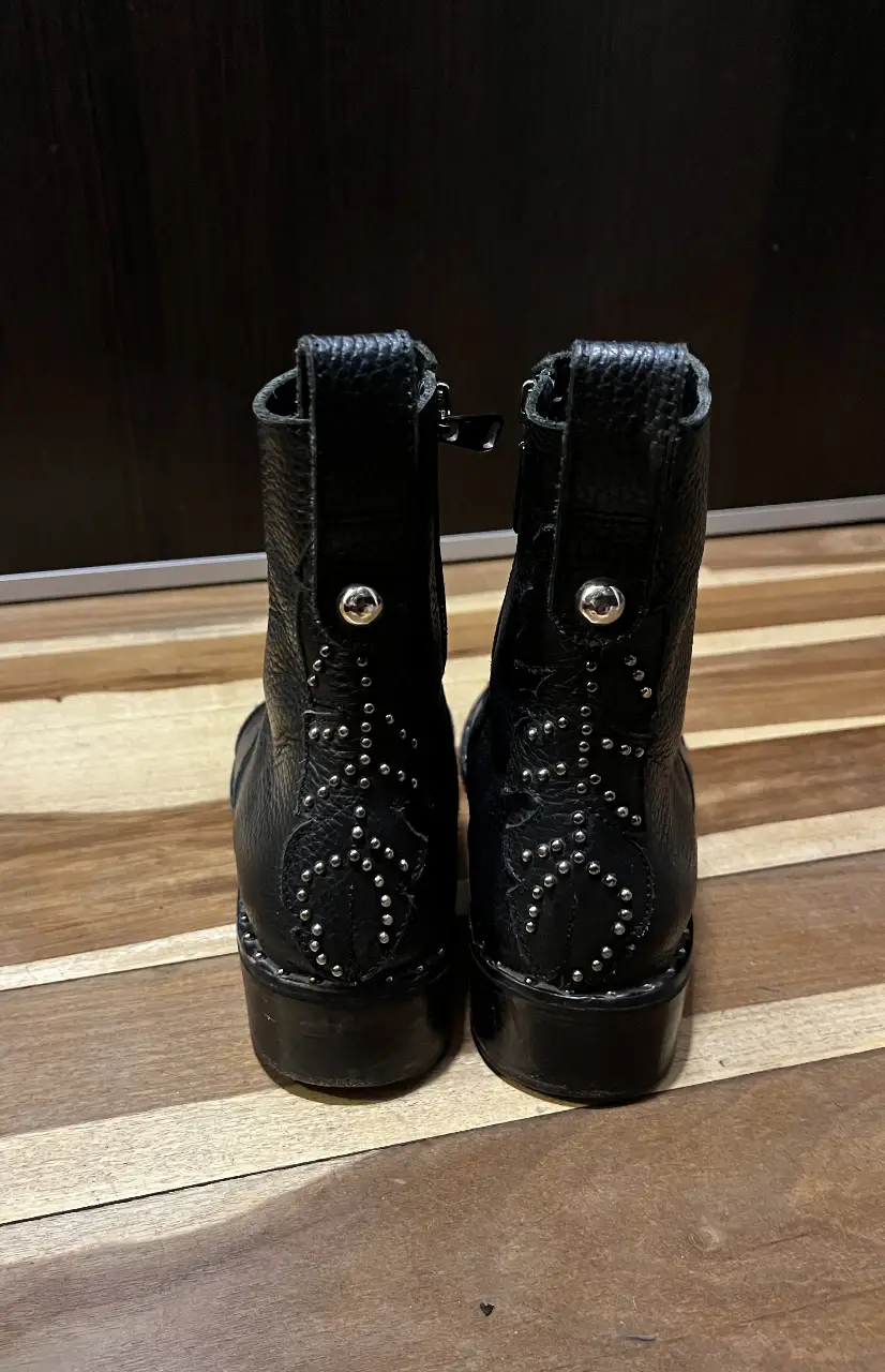 Botines de cuero negro con detalles de tachas plateadas. Diseño moderno y estilo rocker. Ideales para un look casual con un toque audaz.