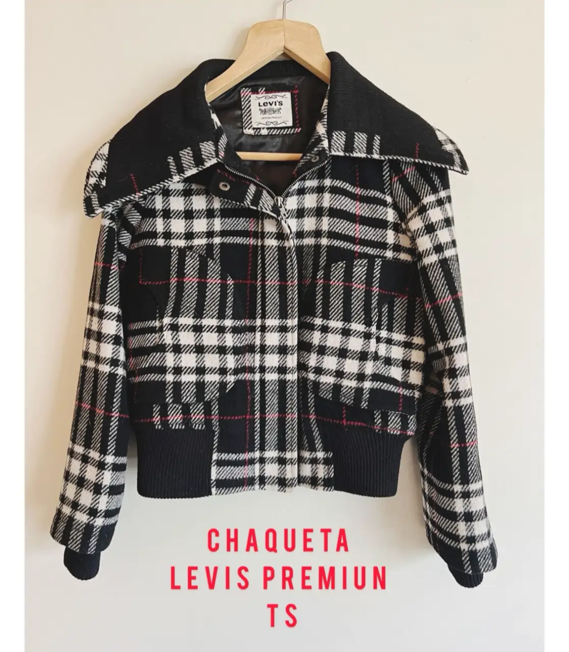 Chaqueta Levi's Premium a cuadros en blanco y negro con detalles en rojo. Diseño con cuello ancho y cierre frontal. Ideal para un look casual y moderno. Lana reciclada ( 61 %)