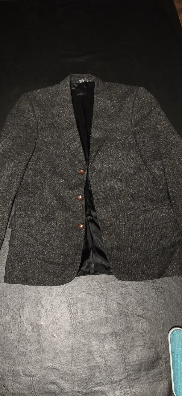 Blazer de vestir gris con detalles de hilos de colores. Posee tres botones al frente y bolsillos con solapa. Marca The London Shop 