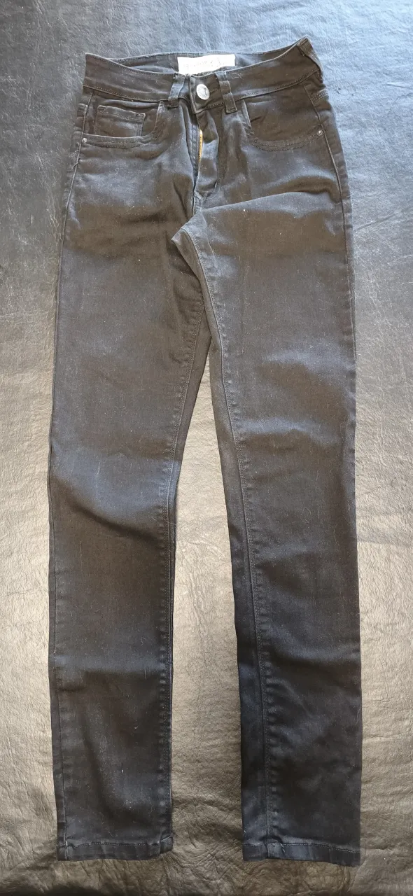 Jeans negros de tiro medio con cinco bolsillos y cierre.