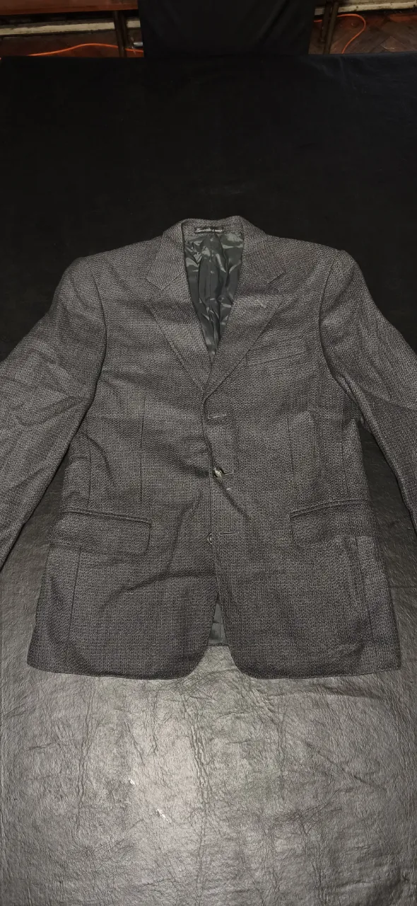 Blazer de lana gris oscuro con tres botones al frente y bolsillos inferiores.