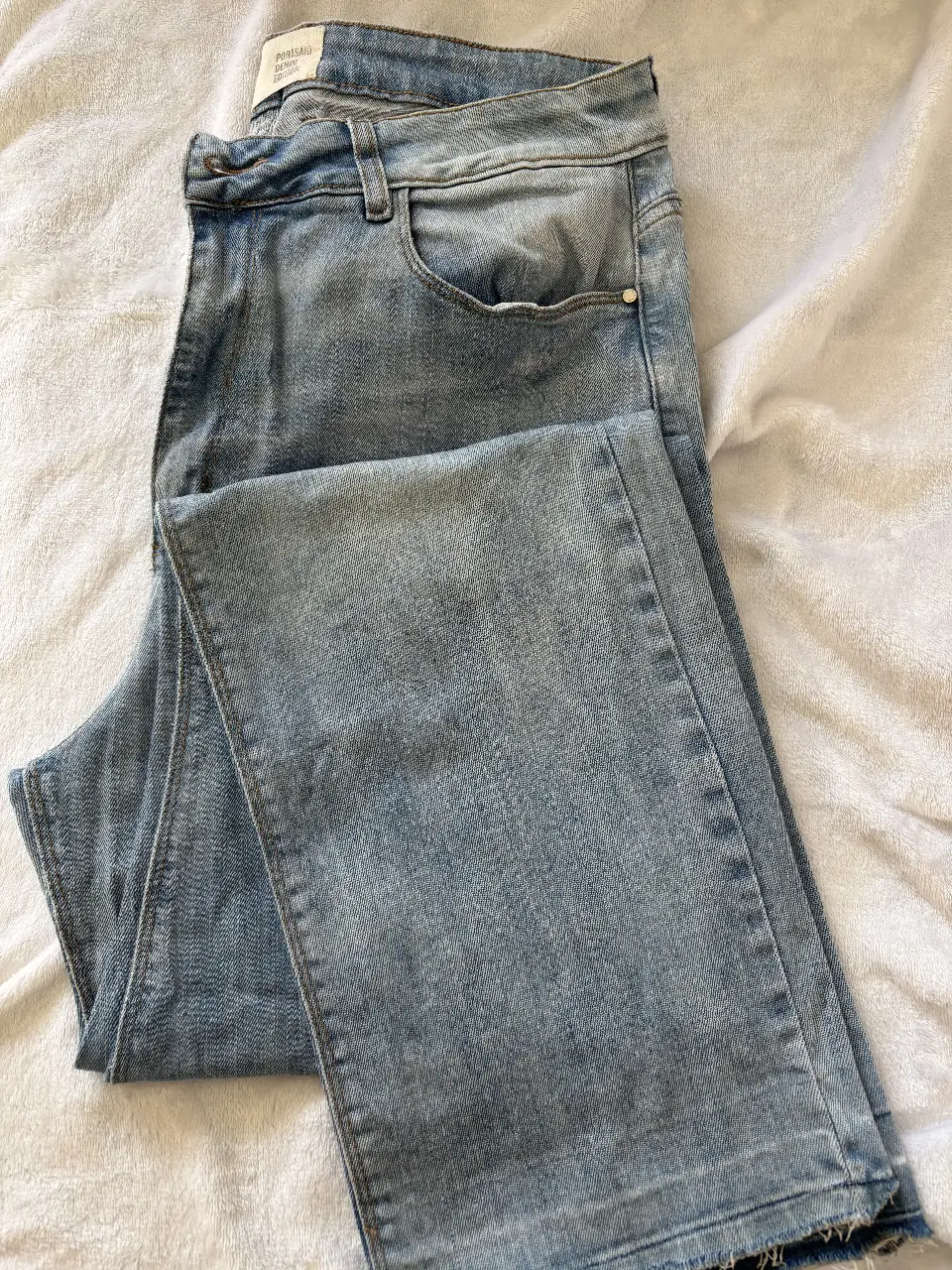 Jeans rectos de hombre, color azul claro, con detalles de desgaste y bolsillos clásicos. Ideal para un look casual y moderno.