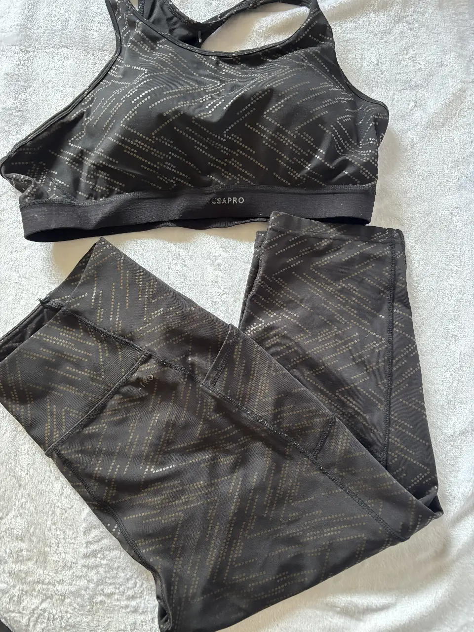 Conjunto deportivo USA Pro negro con estampado geométrico. Incluye top deportivo y calzas. Ideal para entrenamientos y actividades físicas.