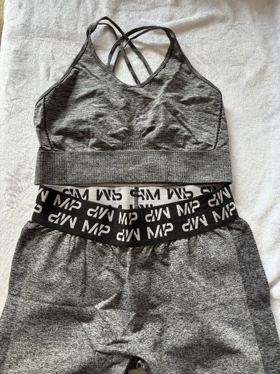 Conjunto deportivo de mujer, top con espalda cruzada y calzas con cintura alta y logo de la marca. Ideal para entrenamientos.