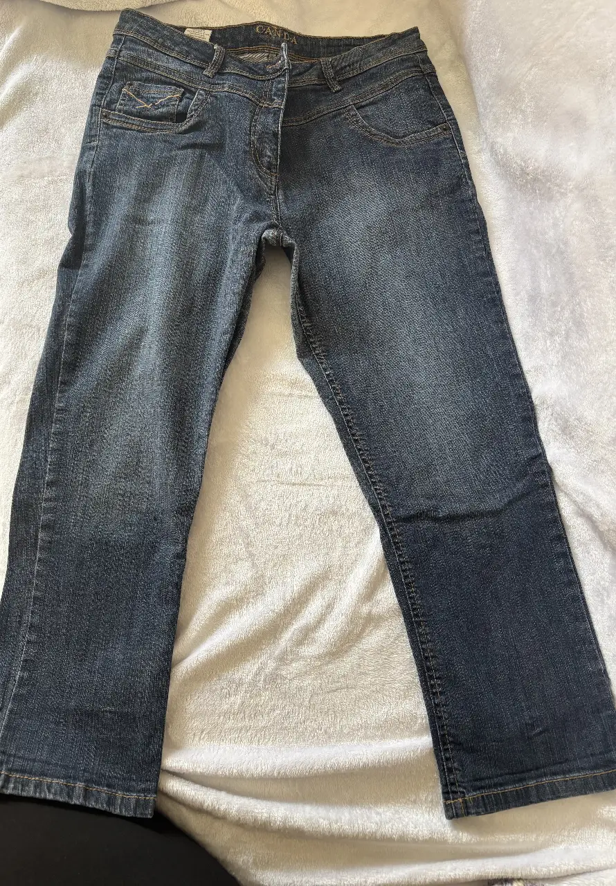 Jeans modelo capri de mujer rectos, de color azul oscuro, con detalles de costura en color ocre. Posee bolsillos delanteros y traseros, y la marca C&A en la cintura.